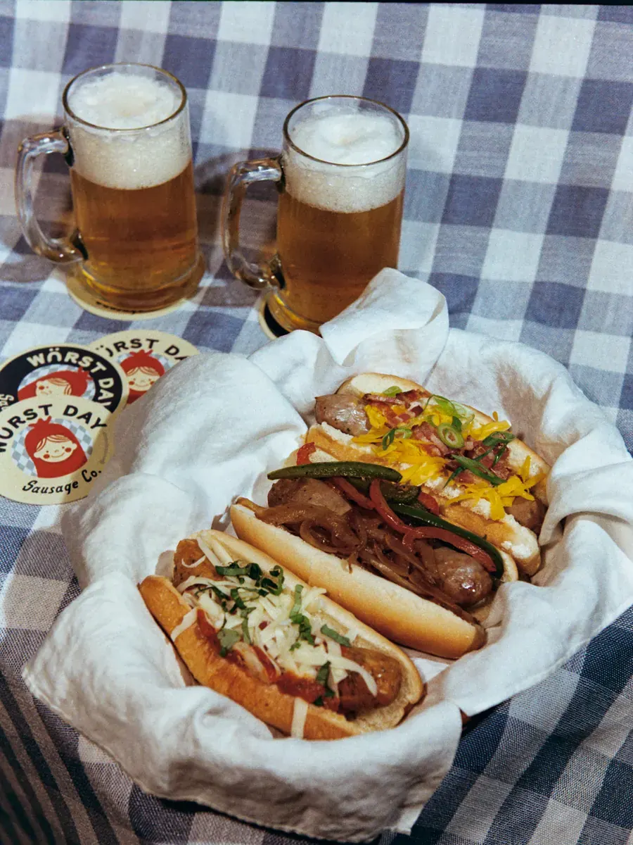 All three Würst Day varieties in a basket, with two steins of beer